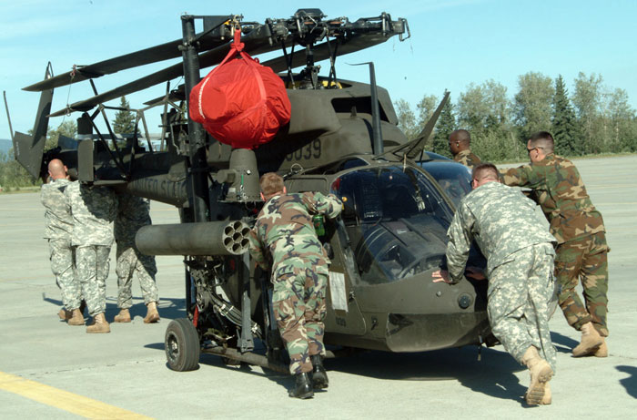 Soldiers from the 6th Squadron, 17th Cavalry Regiment, push a Kiowa helicopter across the airfield on Fort Wainwright